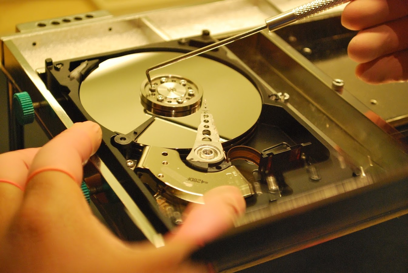 A technician repairing an opened hard drive at a recovery bench